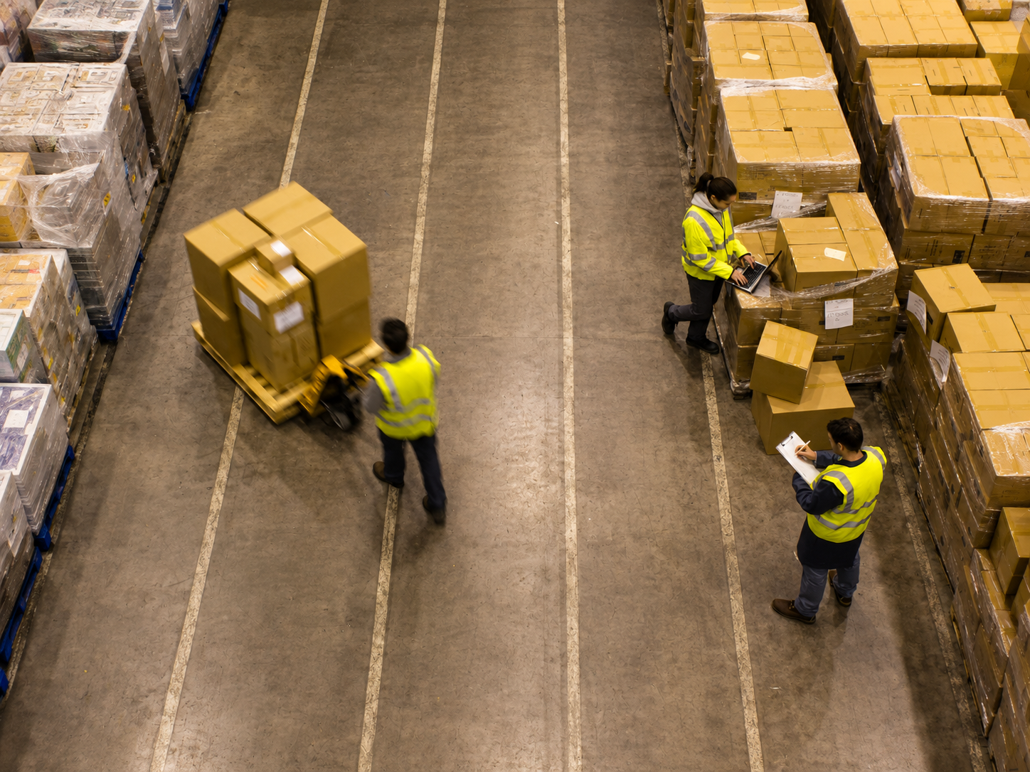 High angle view of warehouse staff sorting inventory between pallet rows