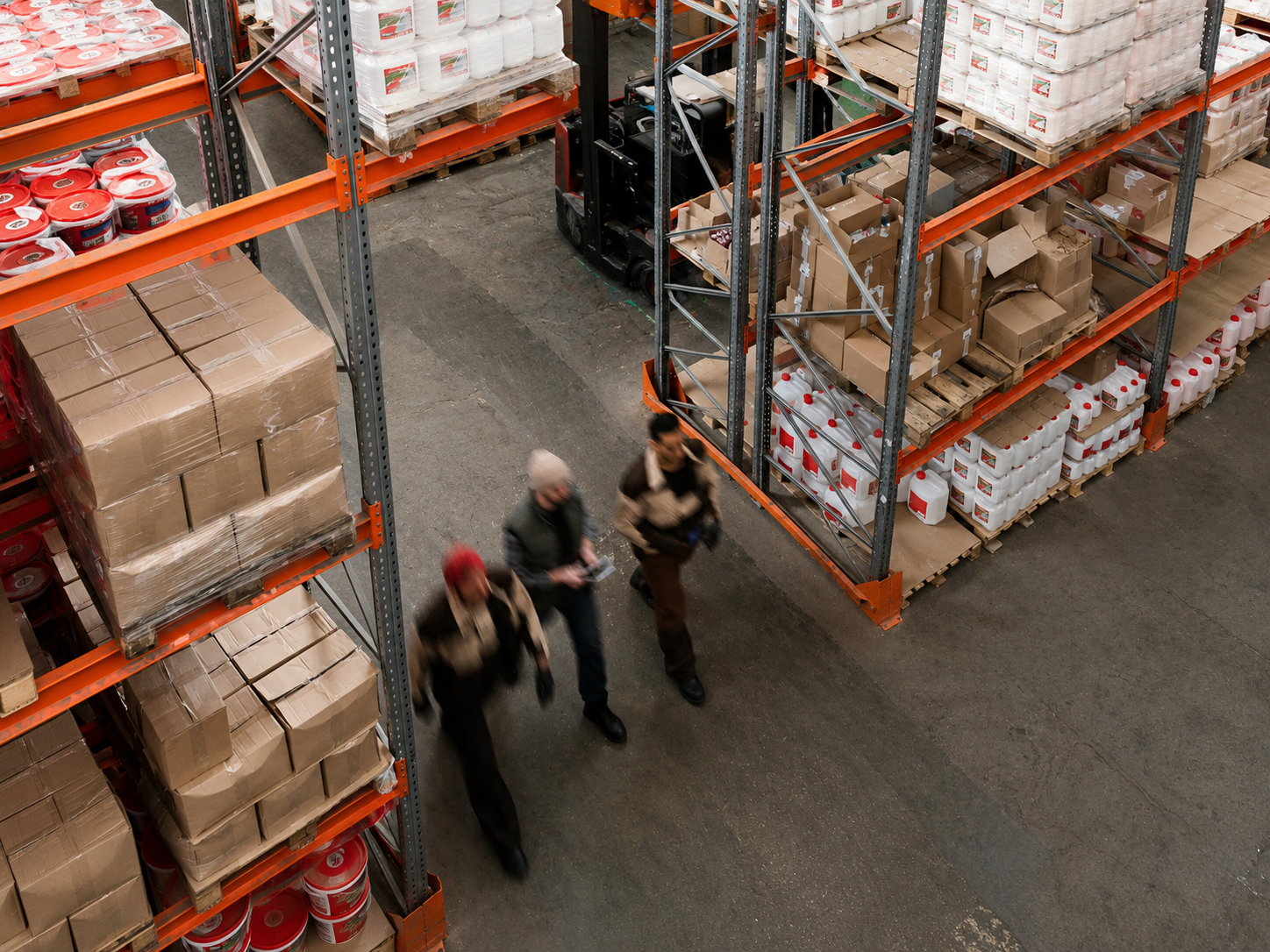Overhead view of a warehouse team walking between stocked pallet racks